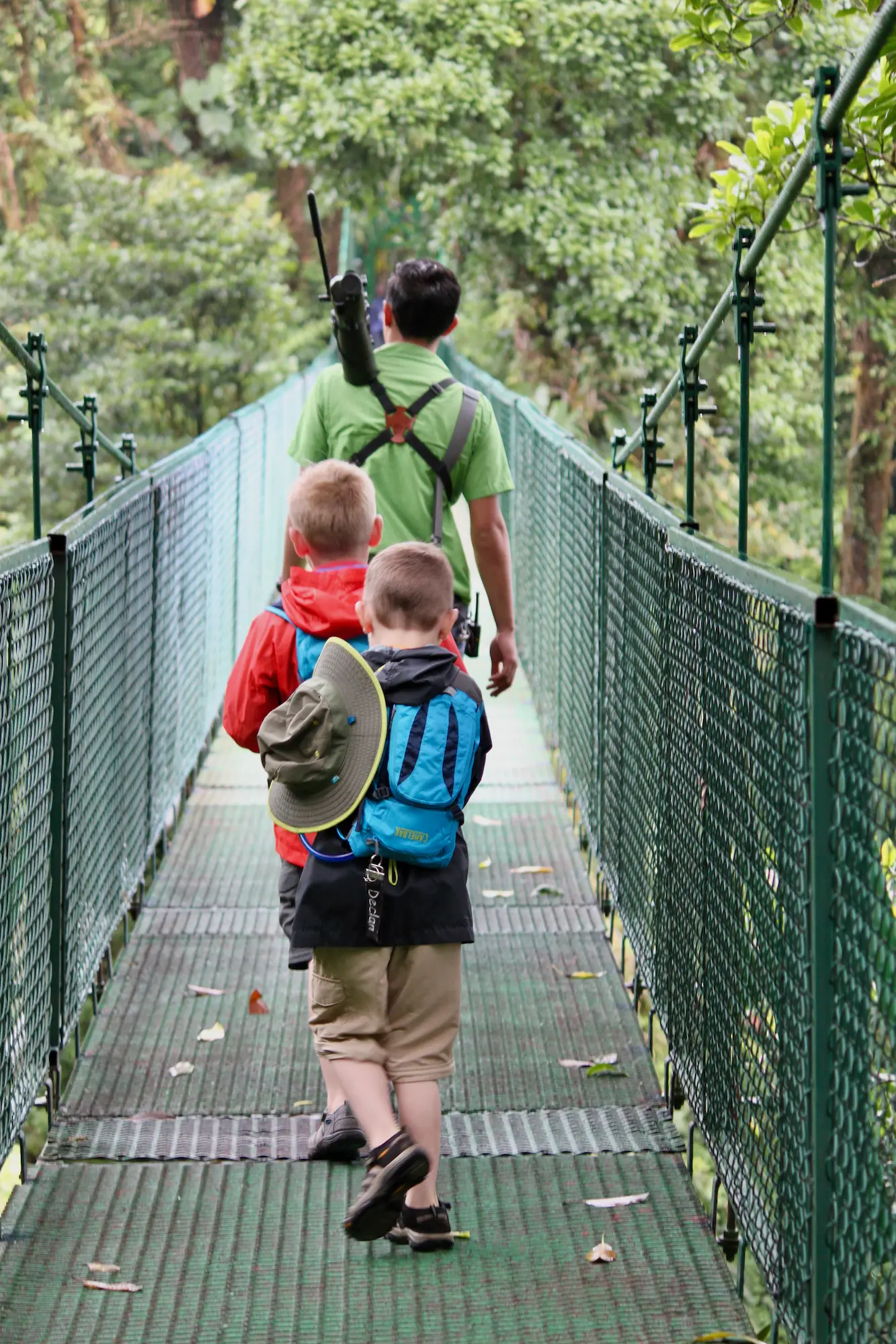father and kids walking on a bridge on a worldschooling adventure